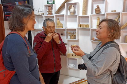 Artesanías. Adolfo Idrovo, investigador y artesano enseña a dos turistas, sus habilidades con los silbatos.