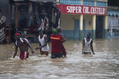 Personas caminan por calles inundadas de Santo Domingo debido al paso de la tormenta tropical Franklin.