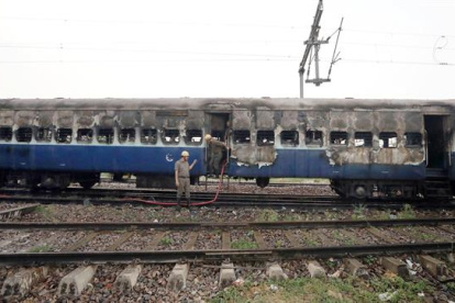 Bomberos indios terminan de extinguir el fuego de un vagón de tren.