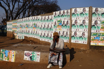 Una mujer posa junto a las imágenes de candidatos en el barrio de Mbare, en Harare, el 21 de agosto.