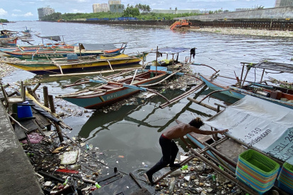 Un pescador fue registrado este 28 de agosto al mover una embarcación rodeada de materiales arrastrados por la corriente, tras el paso del supertifón Saola, en un pueblo pesquero de la ciudad de Paranaque (Metro Manila, Filipinas)