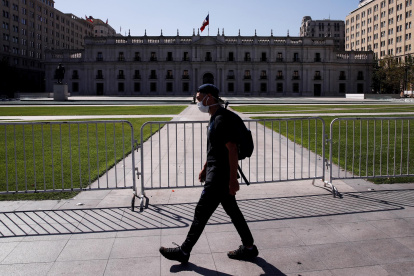 Un hombre camina usando mascarilla frente al Palacio de la Moneda, en Santiago.