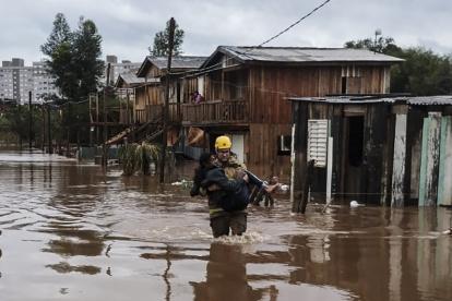 Un bombero rescata a uno de los afectados por las fuertes lluvias, en Passo Fundo.