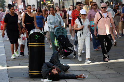 Un hombre sin hogar en la calle Oxford de Londres rodeado de transeúntes, hoy 5 de septiembre de 2023.