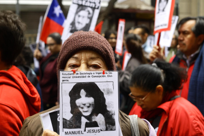 Una mujer muestra el retrato de un desaparecido en la dictadura de Augusto Pinochet.