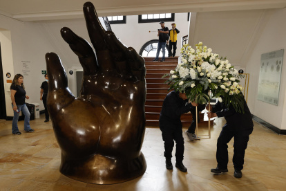 Empleados dejan un arreglo floral junto a la escultura La Mano de Fernando Botero, en el Museo Fernando Botero en Bogotá (Colombia).