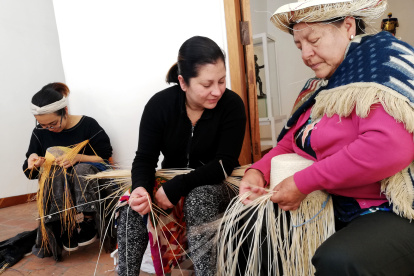 Labores. Blanca Guambaña enseña la forma de ir trenzando las hebras para darle forma al sombrero.