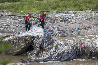 Bomberos trabajan para recuperar los cuerpos de víctimas que fueron arrastradas por el desbordamiento de un río, en el lecho del Río Las Vacas,