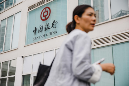 Una mujer camina este lunes frente a un banco en Pekín.