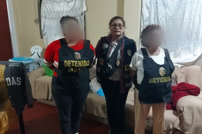 Fotografía cedida este jueves, 5 de octubre, por la Policía Nacional de Perú en la que se registró a una oficial (c) junto a dos detenidas y presuntas integrantes de una facción del grupo criminal transnacional venezolano "Tren de Aragua", en Lima (Perú).