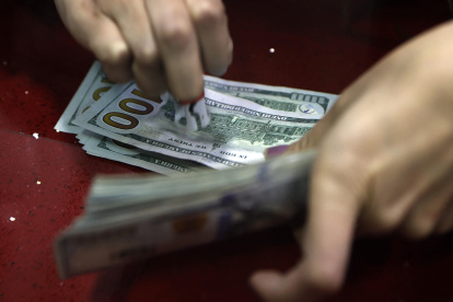 Fotografía de archivo que muestra a una mujer mientras marca billetes de dólares.