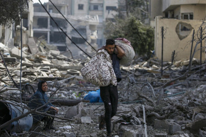 Una mujer palestina (L) sentada entre los escombros del barrio destruido de Al-Ramal tras un ataque aéreo israelí en la ciudad de Gaza, el 10 de octubre de 2023.