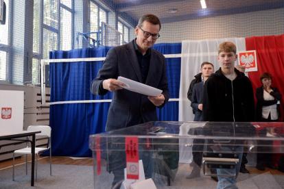 El primer Ministro polaco, Mateusz Morawiecki (c), deposita su voto en Varsovia