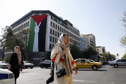 Teherán. Mujeres iraníes caminan junto a una enorme bandera palestina colgada en un edificio en esta capital.