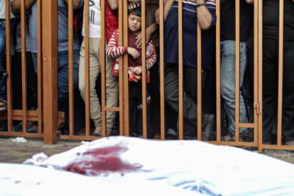 Un niño palestino observa tras unos barrotes los cadáveres de las víctimas cubiertos con sábanas en el hospital Nasser en Khan Yunis, al sur de la Franja de Gaza