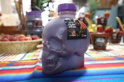 Novedades. Colada morada envasada en una calavera plástica, y pan de muerto junto a las guaguas.