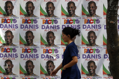Votaciones. Una votante en Cali camina frente a un muro lleno de propaganda electoral. Este proceso se ha caracterizado, además de la violencia, por reunir candidatos llamativos.