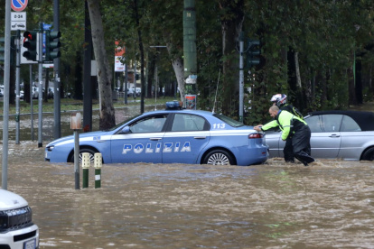 Milán. Un par de agentes empujan a un patrullero, afectado por el agua.