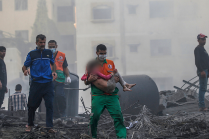 Gaza. Un palestino carga a una niña herida que ha sido recuperada de entre los escombros.