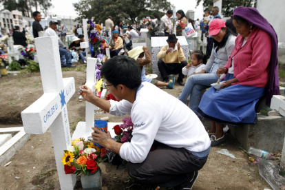 Tradición. Familiares pintan las tumbas de sus muertos, en Calderón.