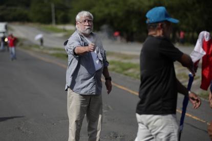 Un hombre dispara un arma hacia un manifestante en medio de un bloqueo de docentes en la vía Panamericana hoy, en Chame (Panamá).