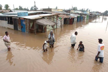 La gente camina por una calle inundada en una ciudad cerca de Nairobi, la capital de Kenia.