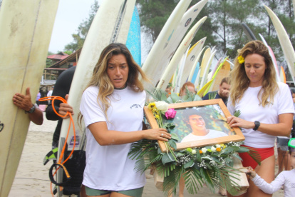 Mimi Barona, hermana de Israel, y la esposa del surfista llevan la ofrenda que se depositó en el mar.