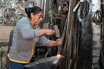 Lucila con el combo y cincel golpea una manija contra el yunque.