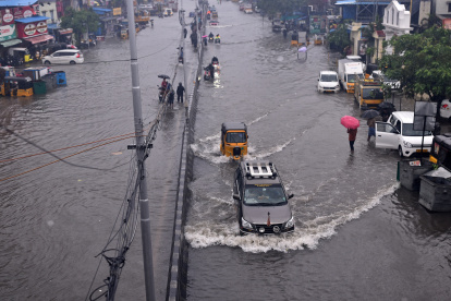 Las personas pasan por una carretera inundada durante las fuertes lluvias, ya que se espera que el ciclón Michaug, en Chennai (India), el 4 de diciembre de 2023.