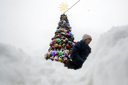 Una mujer camina junto a un árbol de Navidad cubierto de nieve tras una fuerte nevada en Moscú, Rusia, el 15 de diciembre de 2023.