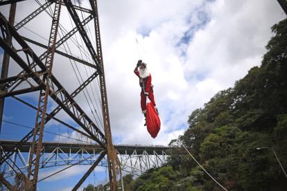 Héctor Chacón, mayor de los Bomberos Municipales, desciende hoy del puente ferroviario Las Vacas durante el acto de entrega de regalos a niñas y niños de escasos recursos del asentamiento Jesús de la Esperanza, en Ciudad de Guatemala (Guatemala).