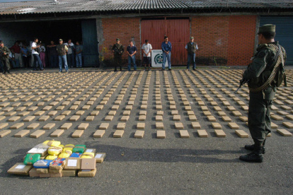 Un agente de la Policía Metropolitana de Cali al custodiar un cargamento de cocaína incautado en un contenedor de fruta, en la zona de carga del aereropuerto Rodrigo Bonilla Aragón, en Cali (Colombia).