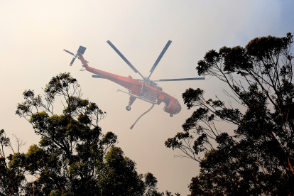 Un helicóptero de los bomberos sobrevuela un incendio forestal en Australia..