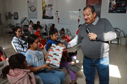 El pastor Juan Fierro (d) reparte regalos a migrantes que pasan la Navidad en el albergue "El buen samaritano", el 24 de diciembre de 2023, en Ciudad Juárez Chihuahua (México).