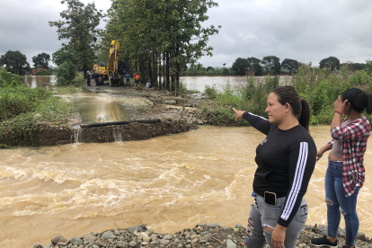 Moradores observan el lugar donde la creciente del río Las Juntas se llevó un tramo de la carretera.