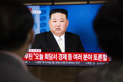 Dos personas viendo en televisión al líder norcoreano Kim Jong-un.