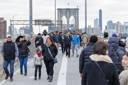 Varias personas caminando por el puente de Brooklyn sin vendedores a la vista en Nueva York.