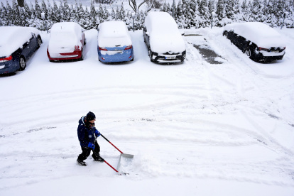 Después de la fuerte nevada de la noche, un hombre trabaja con una pala de nieve para quitar la nieve de las plazas de aparcamiento de un edificio residencial en Estocolmo, Suecia, este 5 de enero de 2024.