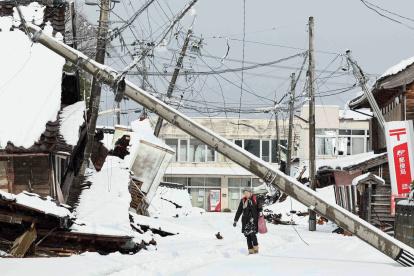 Suzu. Unas personas caminan bajo líneas eléctricas caídas en esta ciudad japonesa, afectada por el terremoto del 1 de enero de 2024.