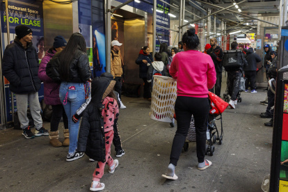 Personas con bolsas de pertenencias y cochecitos abandonan el hotel Row NYC.