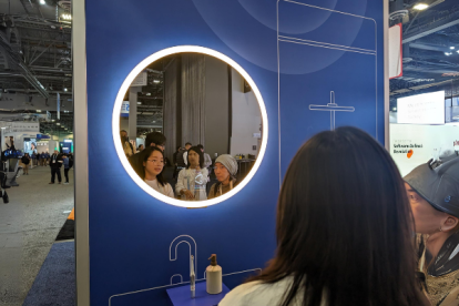 Personas observan hoy el espejo de Baracoda, que usa la IA generativa para aumentar la confianza de los usuarios y su estado de ánimo con mensajes positivos y meditaciones, en la feria tecnológica CES 2024 en Las Vegas, Nevada
