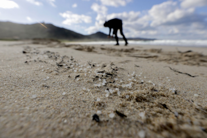 Una persona recoge pellets este jueves, en la playa de Traba, situada en el concello coruñés de Laxe (Galicia).