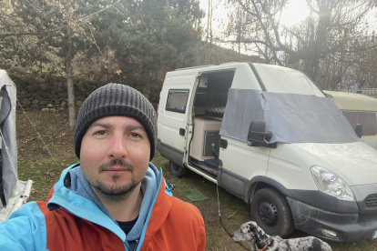 Óscar Fernández Quiles se toma una foto junto a la furgoneta en la que vive. Cataluña enfila el 2024 con un mercado de la vivienda