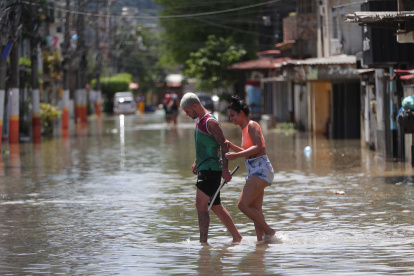 Habitantes transitan hoy por una calle inundada tras las lluvias de los últimos dos días, en el municipio de Duque de Caxias, en la región Baixada Fluminense, área metropolitana de Río de Janeiro (Brasil).