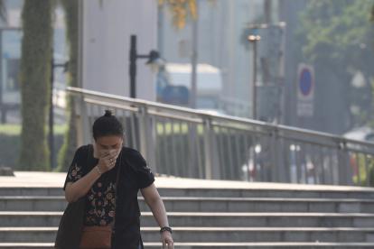 Una persona camina cubriéndose la nariz por una calle céntrica de Bangkok, que este viernes 19 de enero presenta altos niveles "insalubres" de contaminación del aire.