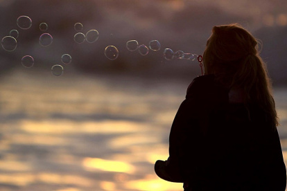 Referencial. una joven en la playa durante el atardecer.