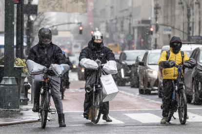 Personas en bicicletas de reparto se abrigaron contra la nieve que caía durante una tormenta de invierno en Nueva York, Nueva York, EE.UU., 19 de enero de 2024.