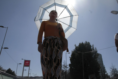 Las personas se cubren del sol con vestimentas largas y sombrilla.