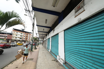 Comercio. Un ciudadano camina por la acera de una calle principal de Quevedo, junto a una serie de locales que permanecen cerrados, por alquilar o vender.