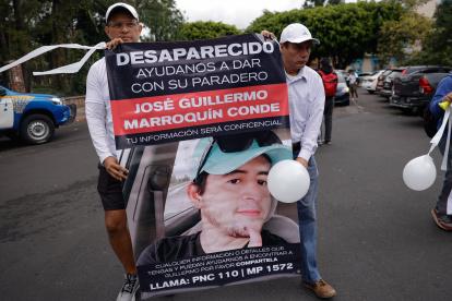 Familiares de Guillermo Marroquín muestran hoy un cartel con su retrato durante una marcha.
